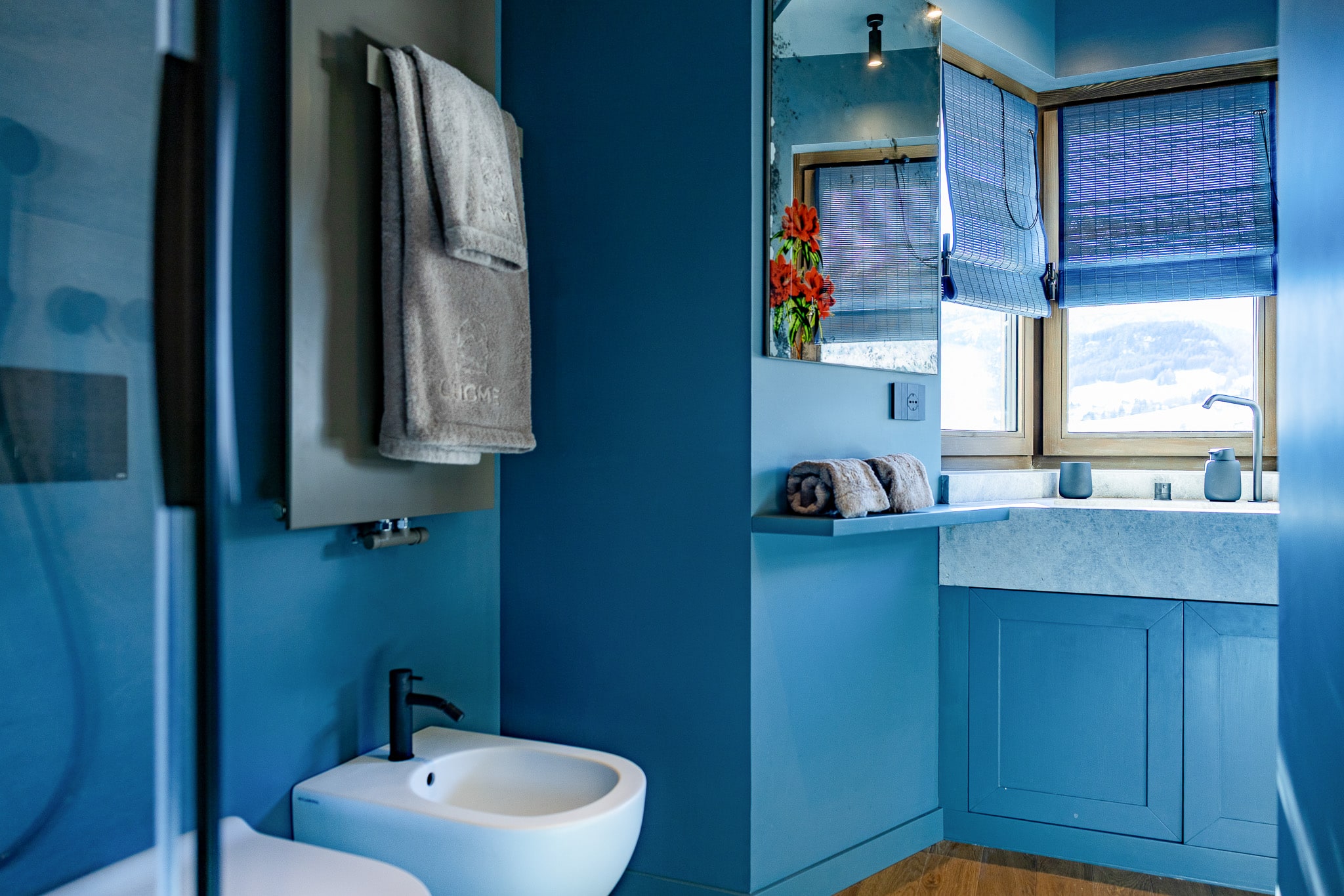 Bagno azzurro con asciugamani L'HOME piegati e lavabo di marmo