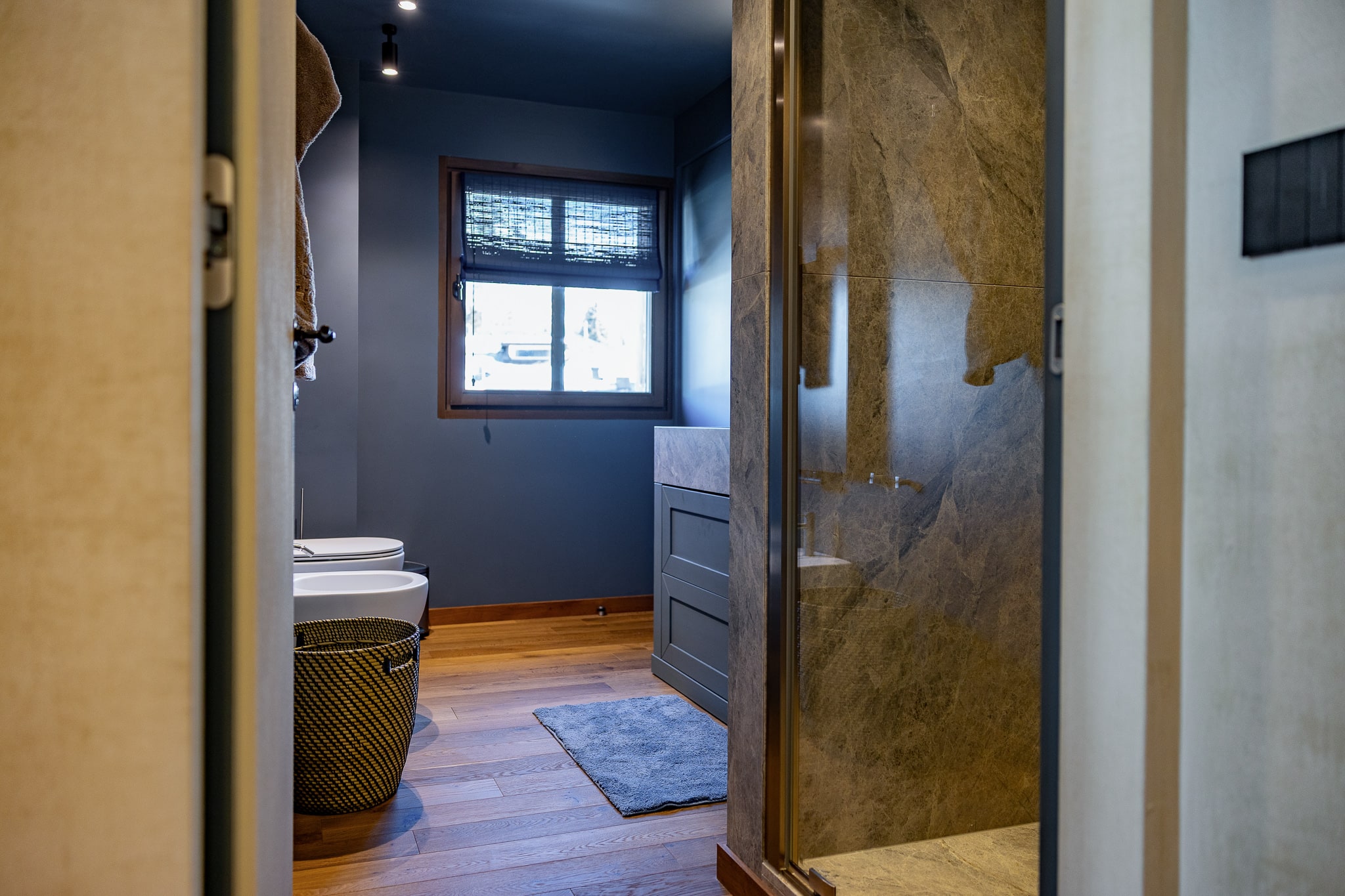 Bagno azzurro con doccia di pietra e porta dorata