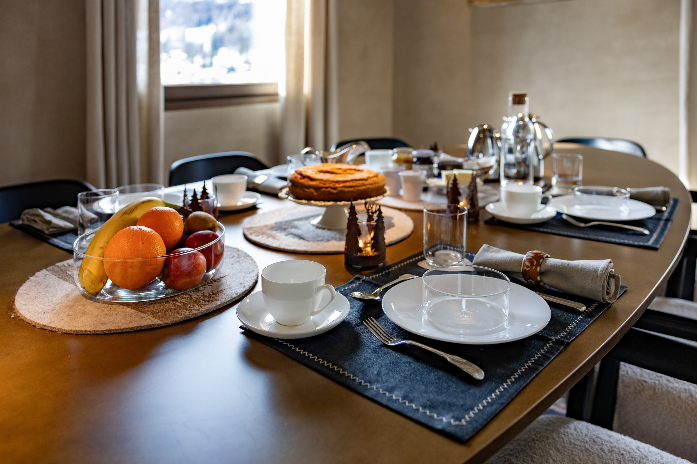 Tavola da pranzo apparecchiata per la colazione con torta, frutta e caffettiera