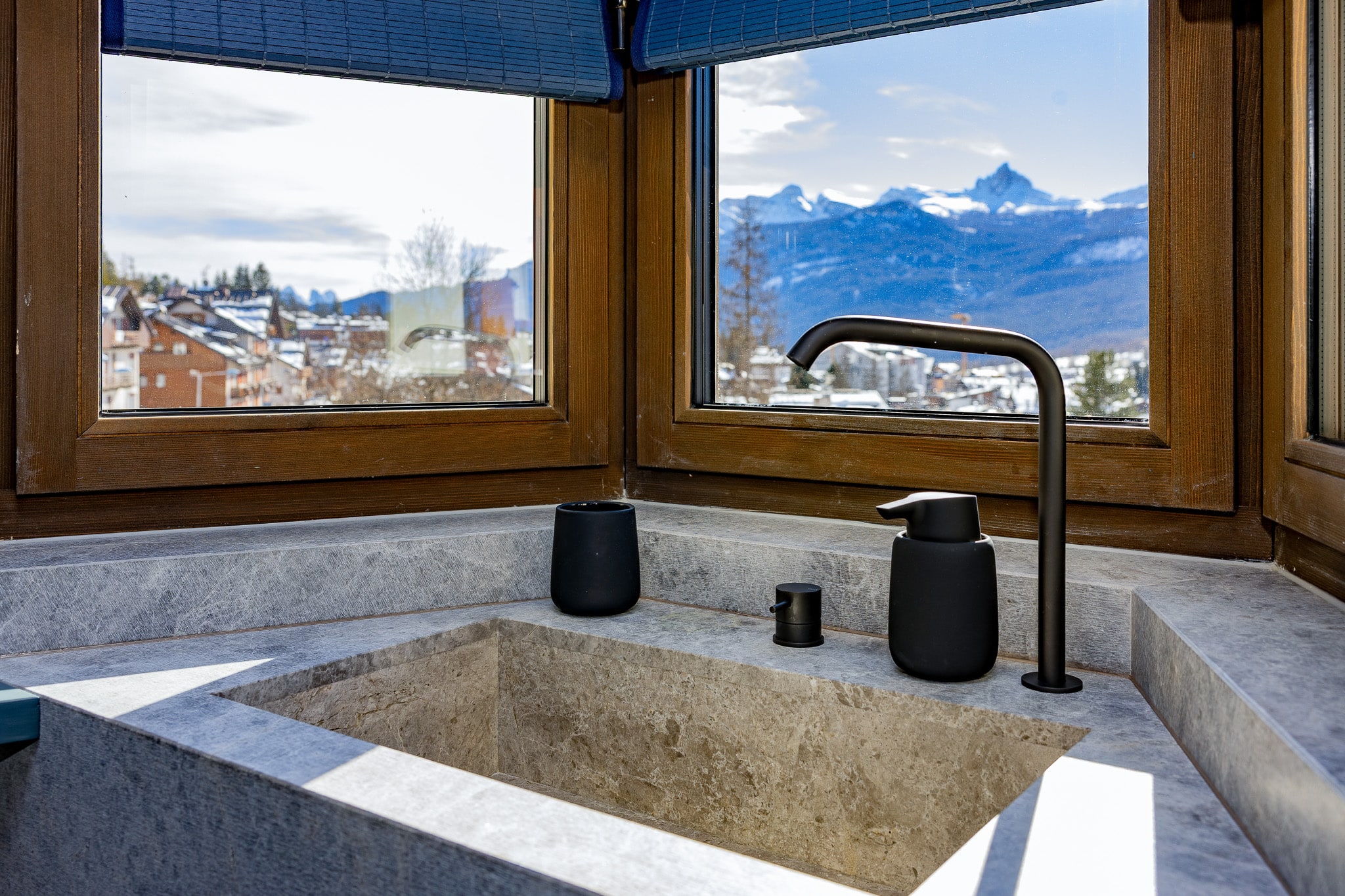 Lavabo in pietra del bagno della suite tra le finestre ad angolo con vista sulle Dolomiti