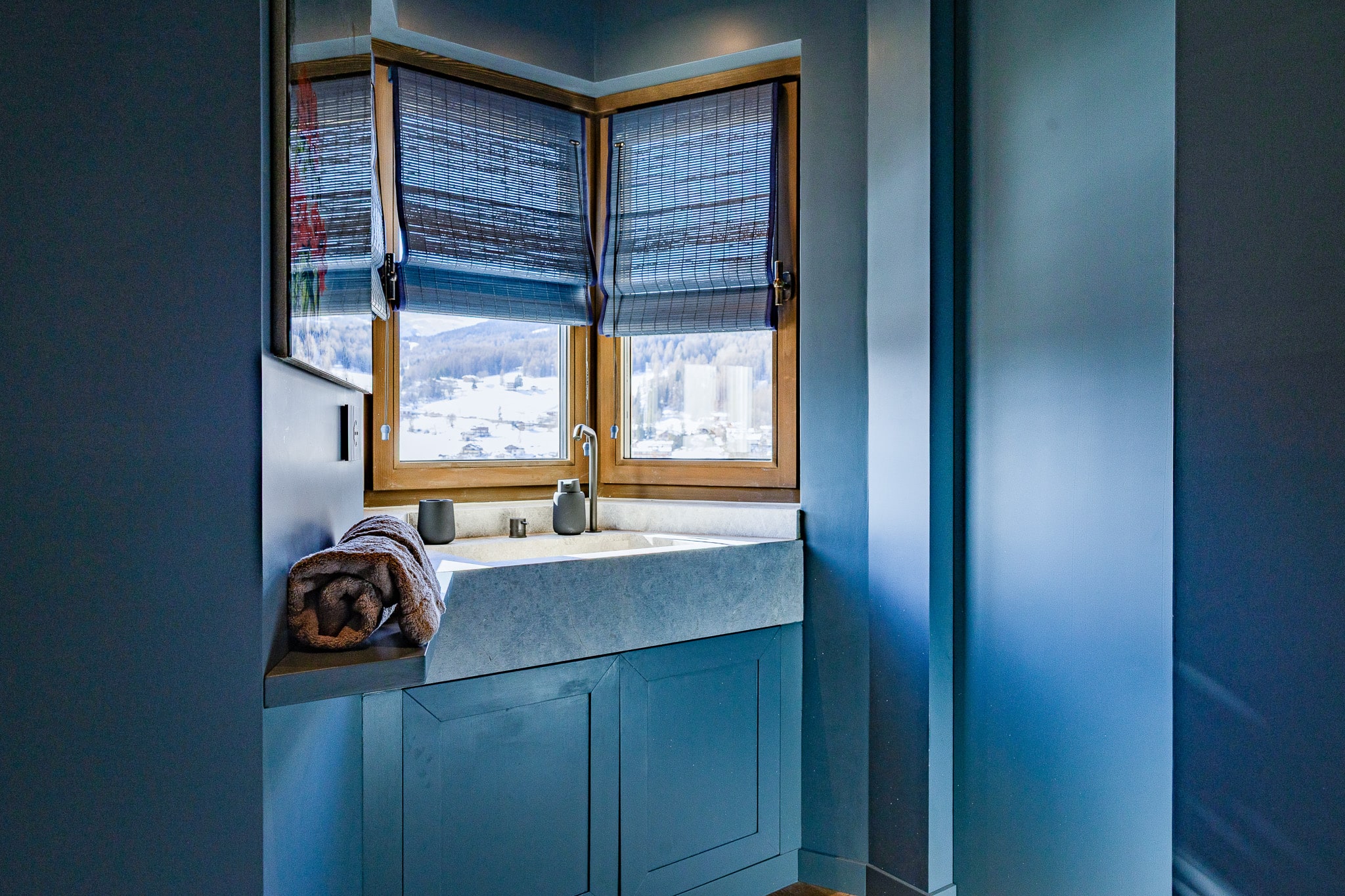 Bagno azzurro della suite con lavabo di marmo sotto la finestra ad angolo
