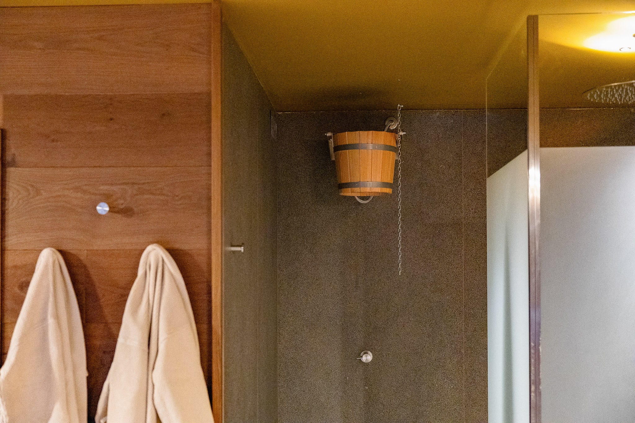 Cabina sauna in legno con secchio e doccia fredda di pietra — rituale alpino tirolese