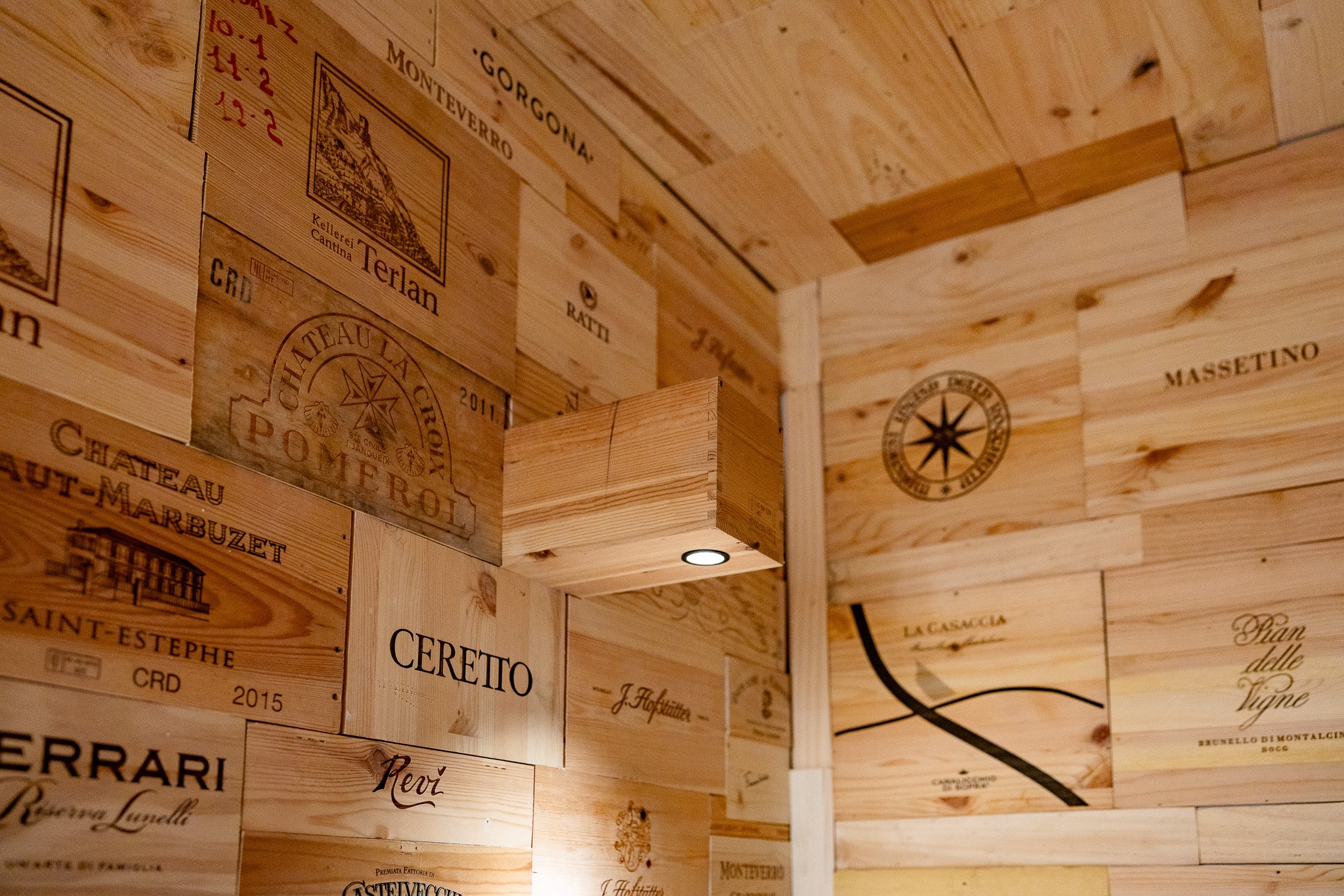 Cantina con pareti di casse di vino: Pomerol, Masseto, Ceretto, Sassicaia