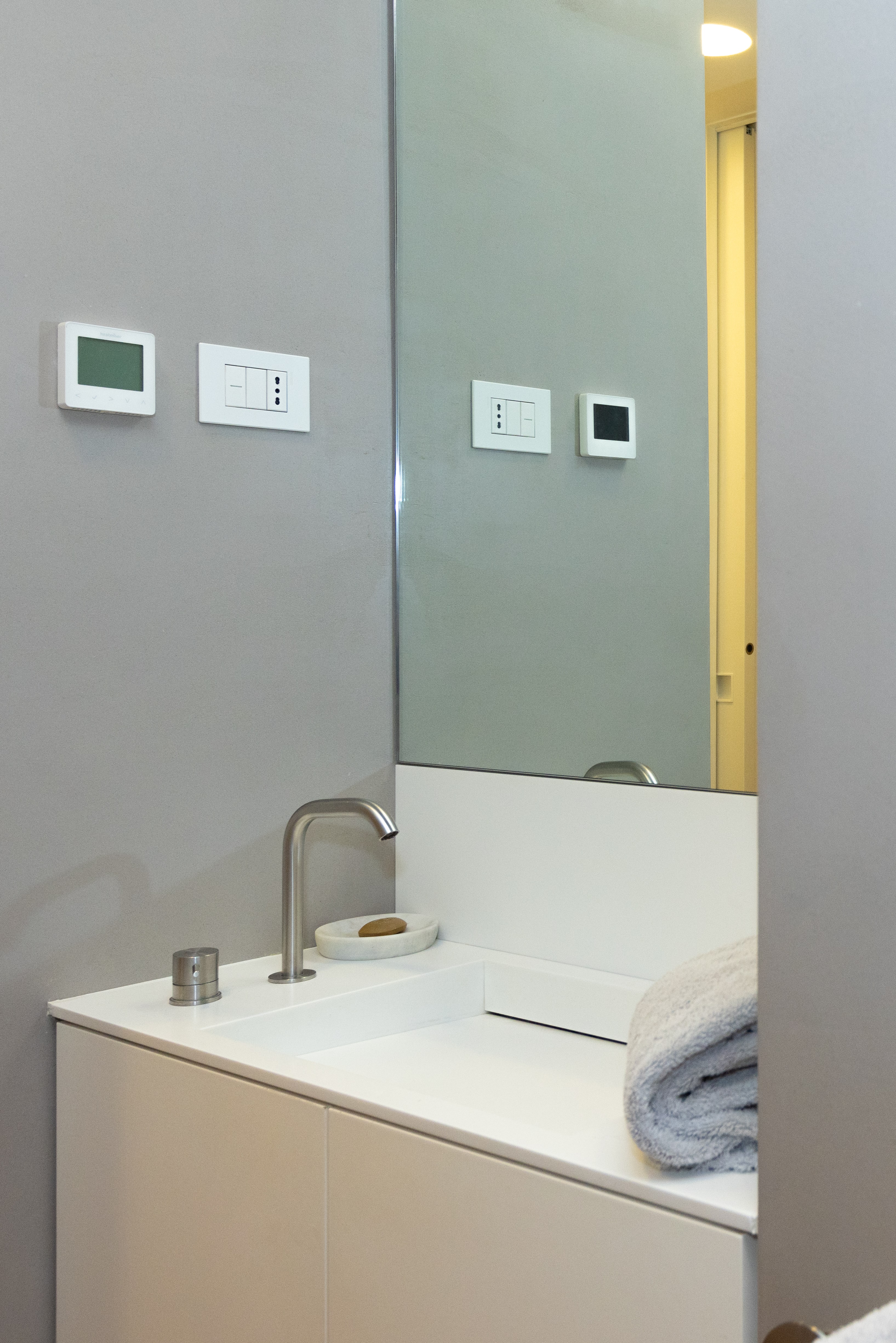 Bagno: lavabo bianco, asciugamani arrotolati e grande specchio