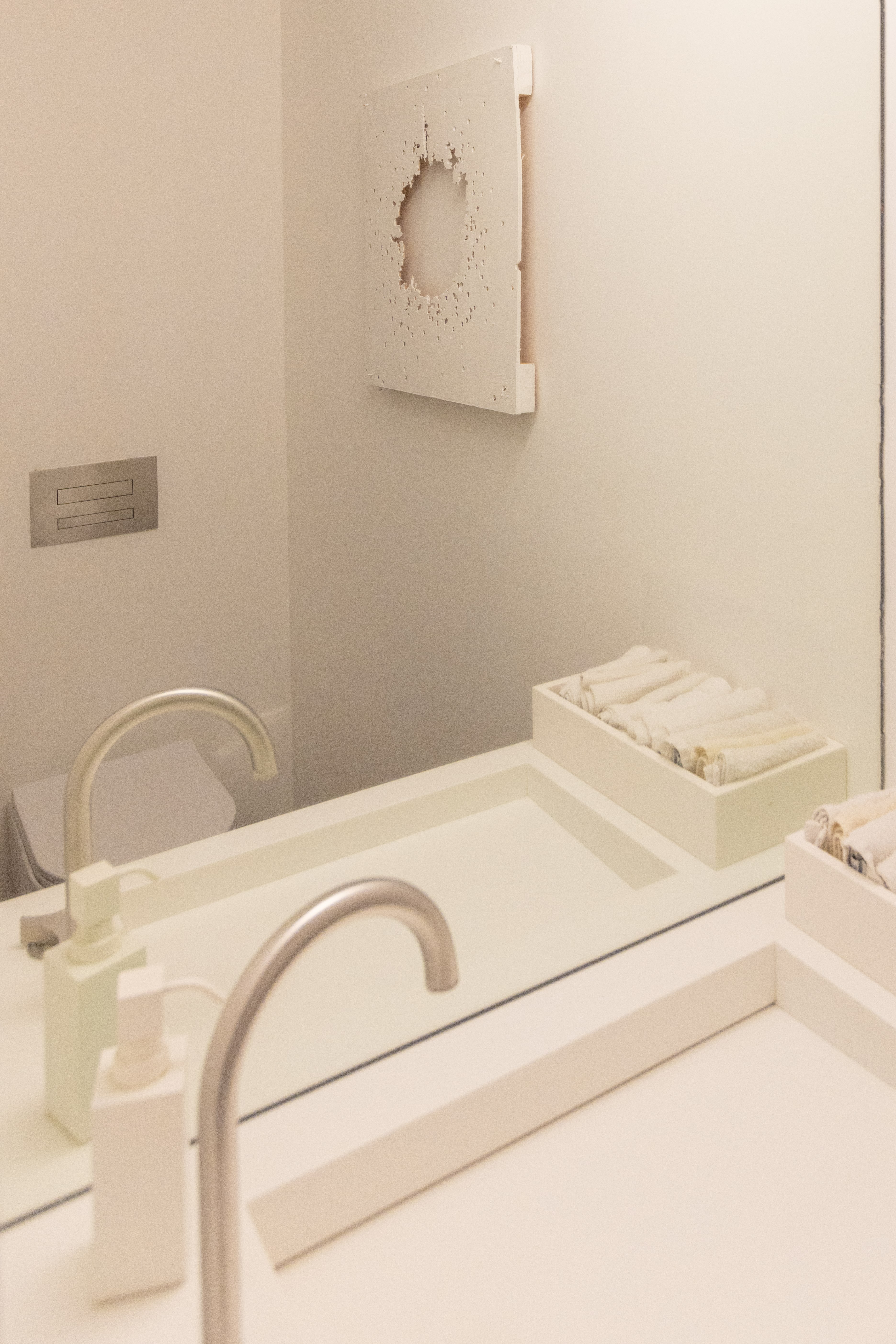 Bagno, dettaglio: opera d'arte traforata sopra il lavabo bianco e asciugamani arrotolati
